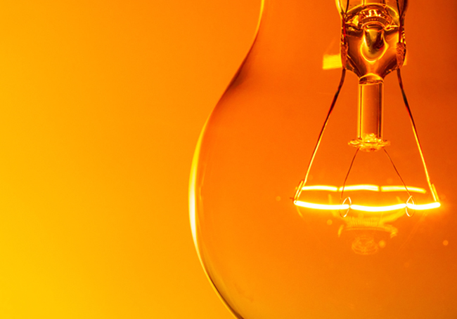 Close up of a lightbulb on an orange background symbolizing ideas and creation